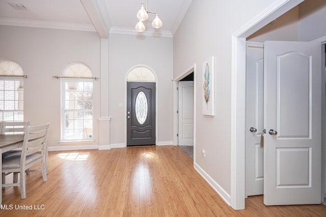 foyer featuring crown molding, a chandelier, light hardwood / wood-style floors, and beamed ceiling