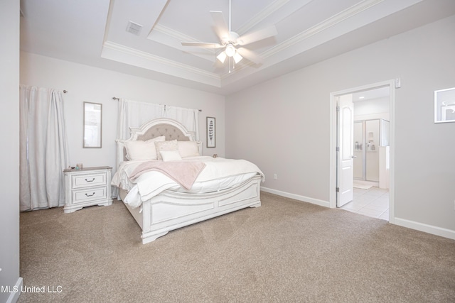 bedroom featuring ensuite bath, ceiling fan, a tray ceiling, ornamental molding, and light colored carpet