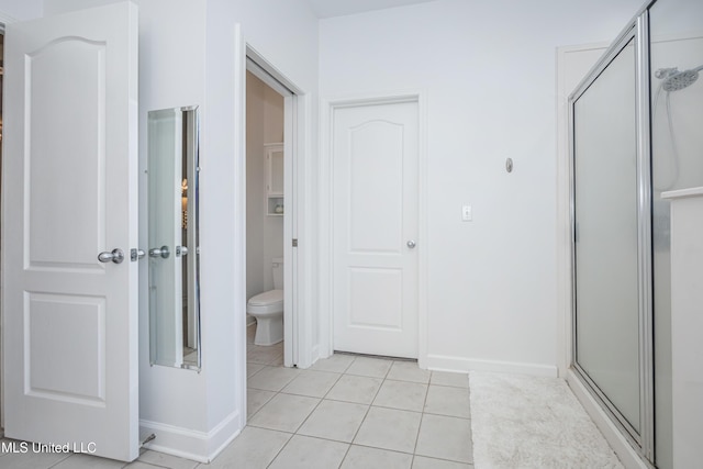 bathroom featuring tile patterned flooring, toilet, and a shower with shower door