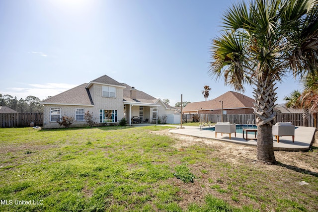 rear view of property featuring a fenced in pool, a patio, and a lawn