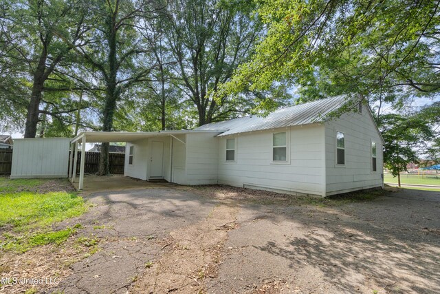 777 W Main St, Senatobia, MS 38668 - rear view of house with asphalt driveway, an attached carport, and an outdoor structure