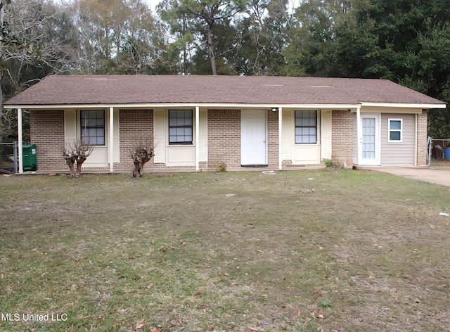 ranch-style house featuring a front yard, brick siding, and roof with shingles