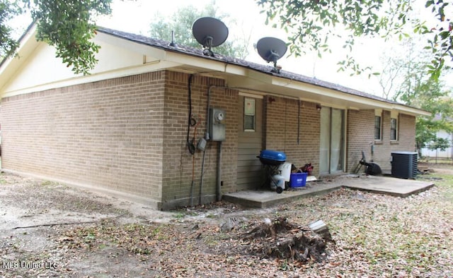 rear view of house featuring brick siding, a patio, and central air condition unit