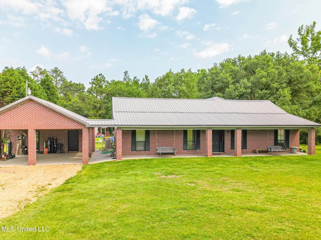 ranch-style house featuring brick siding, metal roof, a carport, and a front yard