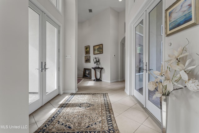 7395 Live Oak Way, Pass Christian, MS 39571 - entrance foyer with french doors, light tile patterned floors, arched walkways, baseboards, and inlaid floor details