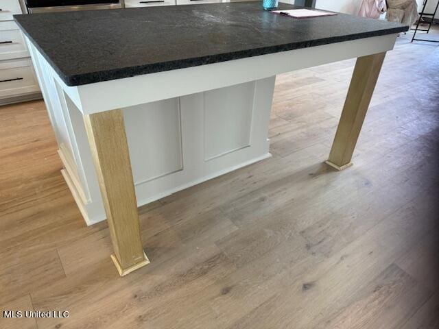 317 Willow Way Unit 158, Canton, MS 39046 - details featuring dark countertops, light wood-type flooring, a kitchen island, and white cabinetry