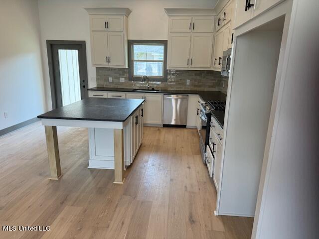 317 Willow Way Unit 158, Canton, MS 39046 - kitchen with tasteful backsplash, appliances with stainless steel finishes, dark countertops, a sink, and light wood-type flooring