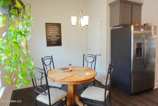 dining space featuring dark wood-style floors, a notable chandelier, and baseboards