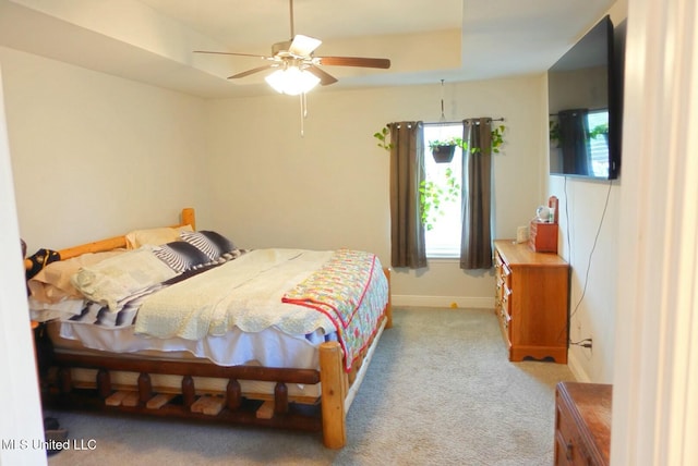 bedroom featuring carpet flooring, a raised ceiling, a ceiling fan, and baseboards