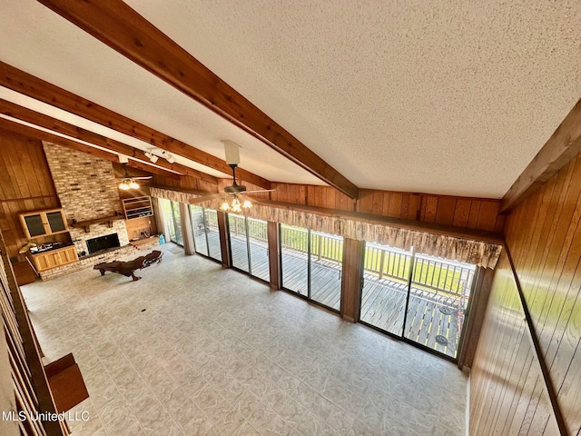 577 W Lakeshore Dr, Carriere, MS 39426 - unfurnished living room featuring wood walls, a ceiling fan, beamed ceiling, a textured ceiling, and a fireplace