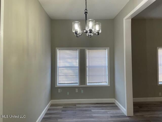 unfurnished dining area featuring a notable chandelier and dark wood-type flooring