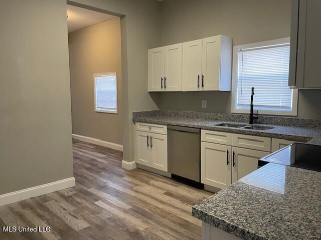 kitchen featuring stainless steel dishwasher, sink, white cabinetry, and light hardwood / wood-style floors