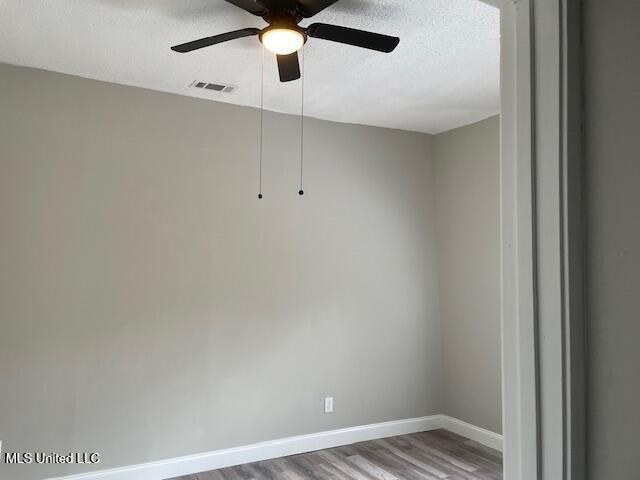 empty room with a textured ceiling, ceiling fan, and wood-type flooring