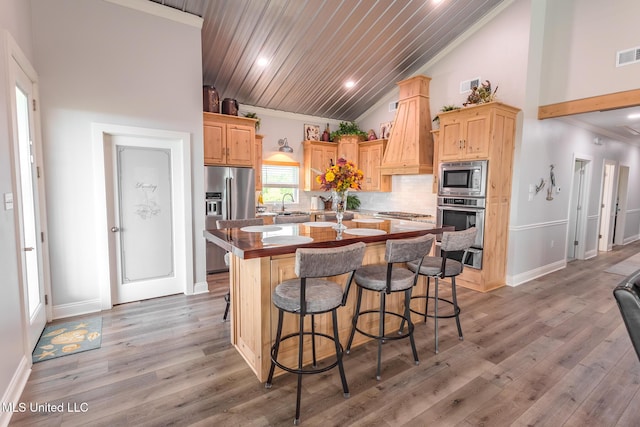 5004 Oak St, Bay Saint Louis, MS 39520 - kitchen with appliances with stainless steel finishes, light brown cabinets, a center island with sink, vaulted ceiling, and decorative backsplash
