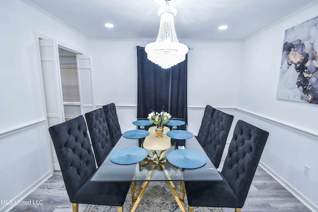 dining room featuring wood-type flooring, ornamental molding, and an inviting chandelier