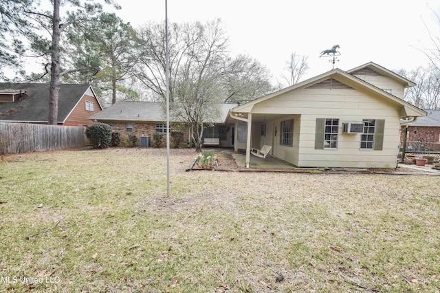 rear view of property featuring an AC wall unit, a lawn, and central AC unit