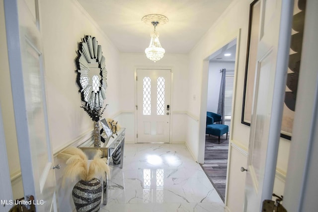 foyer entrance with crown molding and a chandelier