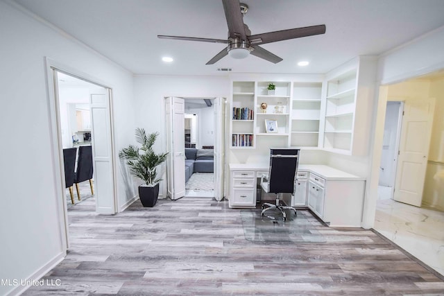 home office featuring built in desk, light hardwood / wood-style floors, and ceiling fan