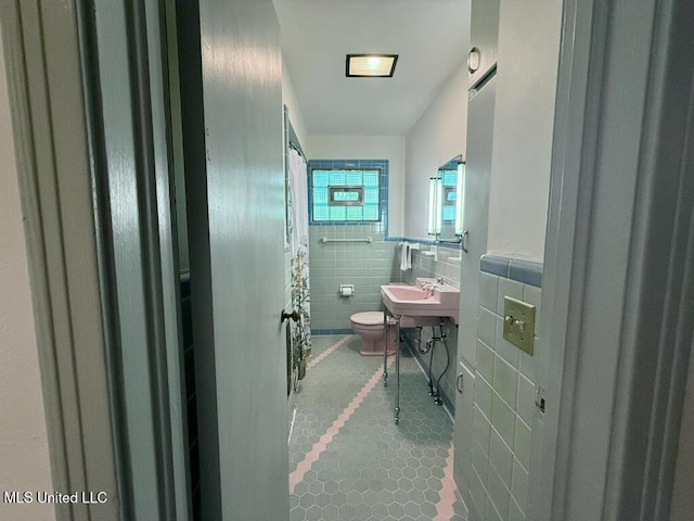 bathroom with toilet, tile walls, tile patterned flooring, and a wainscoted wall