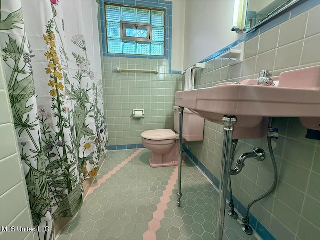 full bath with tile patterned flooring, a shower with curtain, toilet, and tile walls