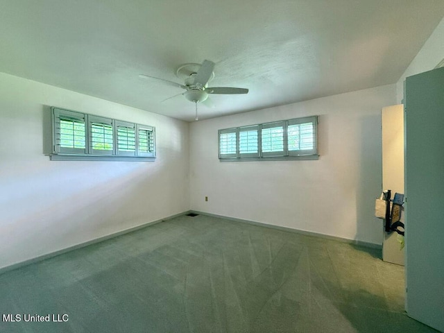 carpeted spare room featuring ceiling fan and baseboards