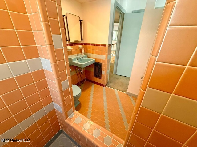 bathroom featuring tile patterned flooring, a wainscoted wall, toilet, and tile walls