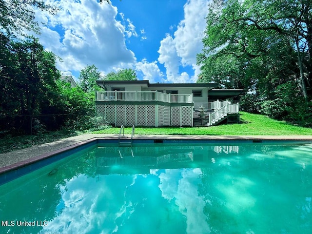 outdoor pool with a lawn, a wooden deck, and stairway