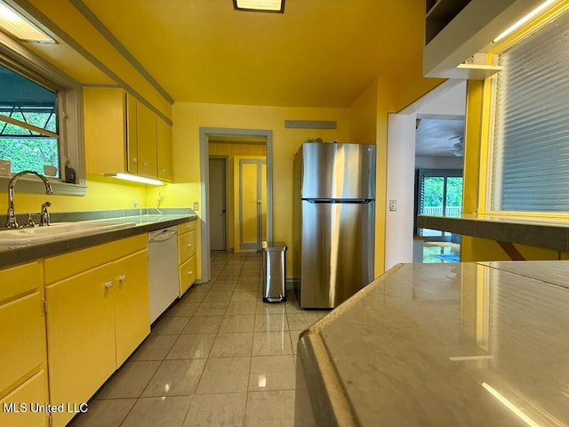 kitchen with freestanding refrigerator, a sink, light tile patterned floors, and dishwasher