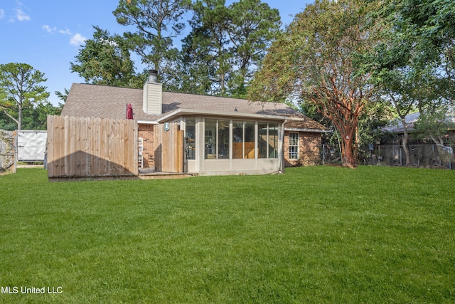 rear view of house featuring a sunroom and a yard