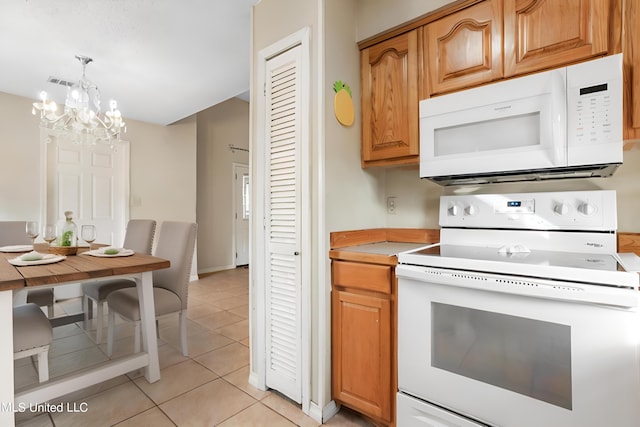 kitchen featuring hanging light fixtures, white appliances, a notable chandelier, and light tile patterned flooring