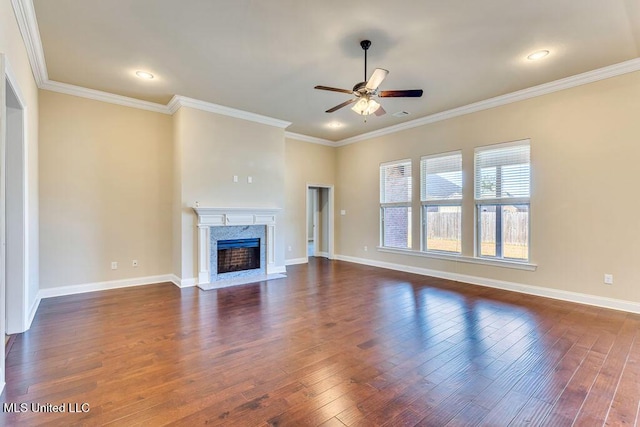 unfurnished living room featuring ceiling fan, a high end fireplace, ornamental molding, and dark hardwood / wood-style flooring