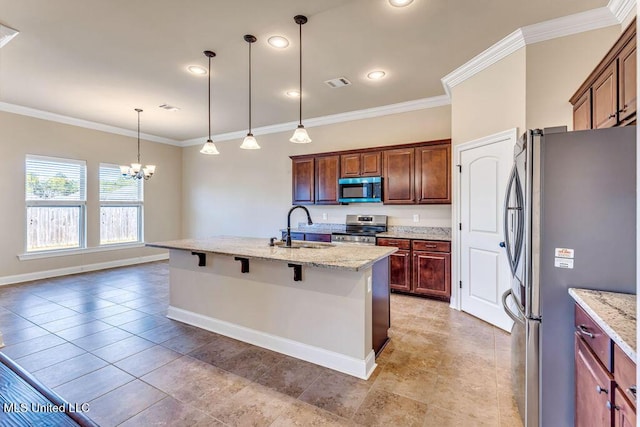 kitchen featuring appliances with stainless steel finishes, light stone counters, a breakfast bar, and decorative light fixtures