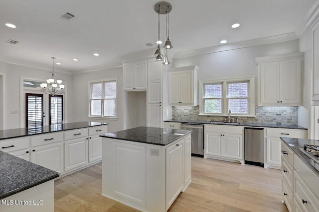 kitchen featuring white cabinets, appliances with stainless steel finishes, a center island, and hanging light fixtures