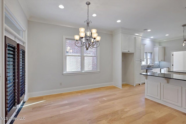 kitchen featuring light hardwood / wood-style floors, crown molding, white cabinets, and hanging light fixtures