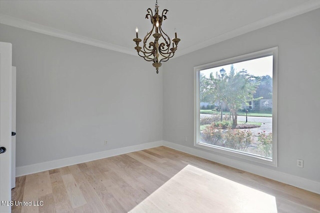 spare room featuring crown molding, a healthy amount of sunlight, light hardwood / wood-style flooring, and a chandelier