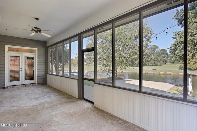 unfurnished sunroom featuring french doors, a water view, and ceiling fan