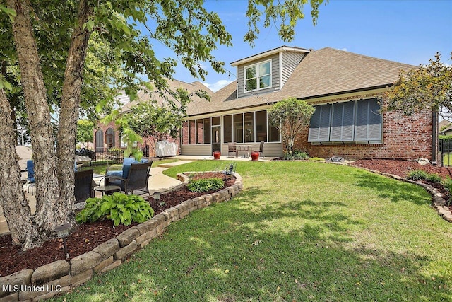 back of house with a sunroom, a patio area, and a lawn