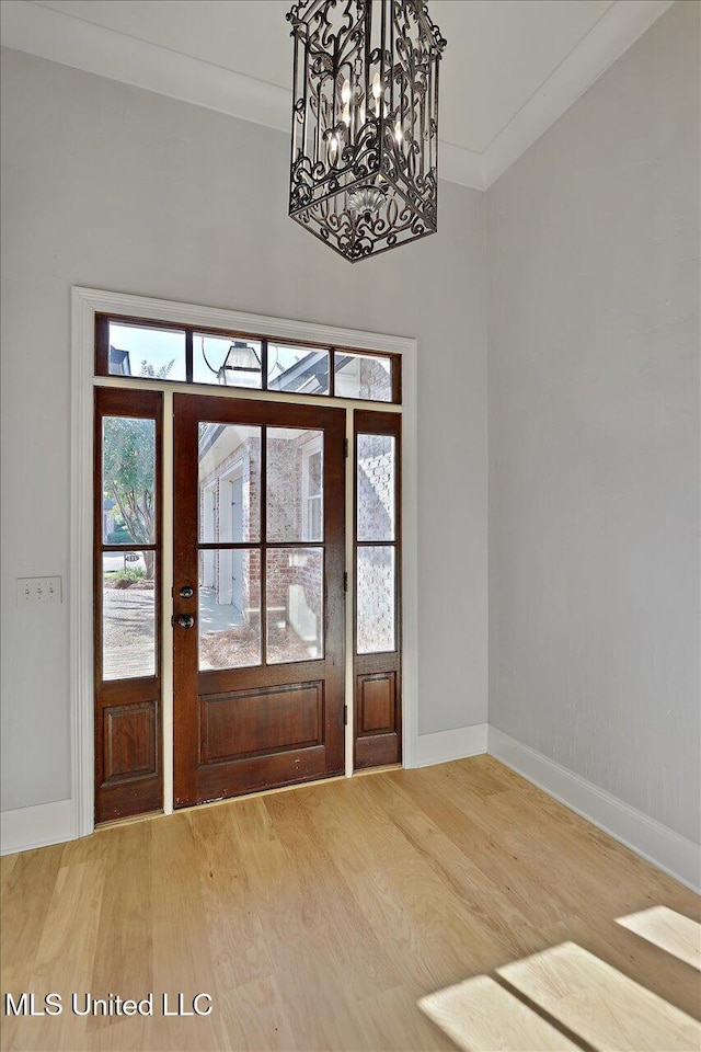 entrance foyer featuring ornamental molding, hardwood / wood-style floors, and a chandelier