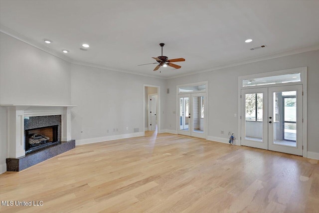 unfurnished living room with french doors, crown molding, and light wood-type flooring