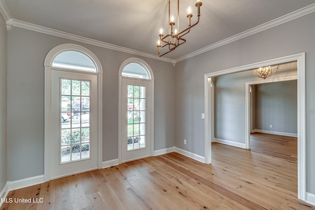 entryway with a notable chandelier, crown molding, baseboards, and wood-type flooring