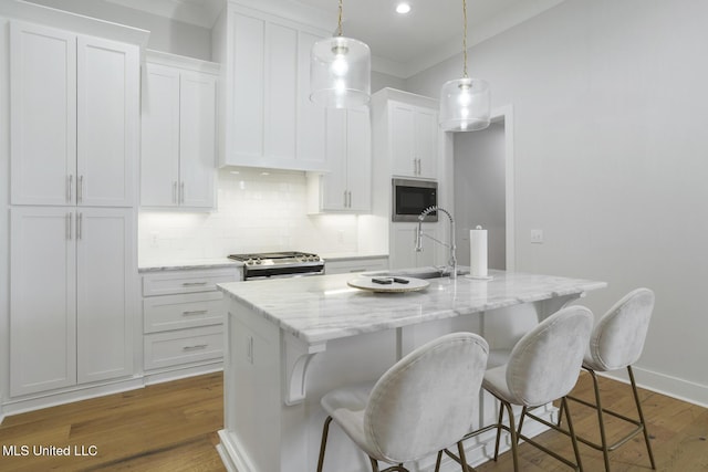 168 Shore View Dr, Madison, MS 39110 - kitchen with stainless steel microwave, range, a kitchen island with sink, backsplash, and white cabinets