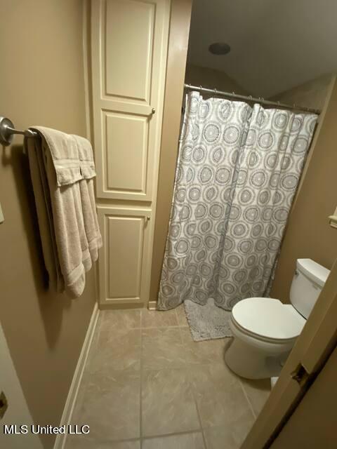 bathroom with tile patterned flooring, curtained shower, and toilet