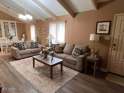 living room featuring lofted ceiling with beams, wood finished floors, and a notable chandelier
