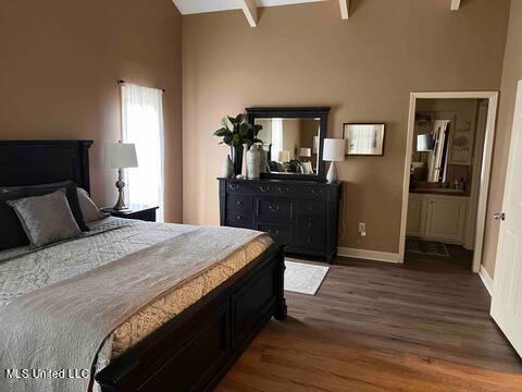 bedroom featuring beam ceiling, ensuite bathroom, dark hardwood / wood-style floors, and high vaulted ceiling