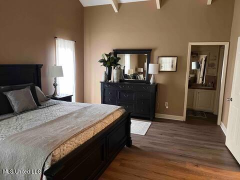 bedroom with high vaulted ceiling, baseboards, ensuite bath, and wood finished floors