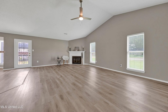 10326 Amanda Dr, Olive Branch, MS 38654 - unfurnished living room featuring a ceiling fan, light wood-style flooring, vaulted ceiling, and a glass covered fireplace