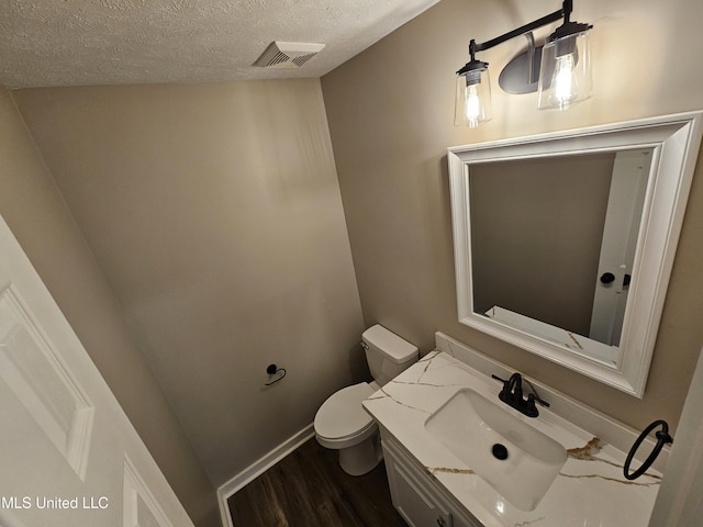 bathroom with vanity, toilet, wood-type flooring, and a textured ceiling