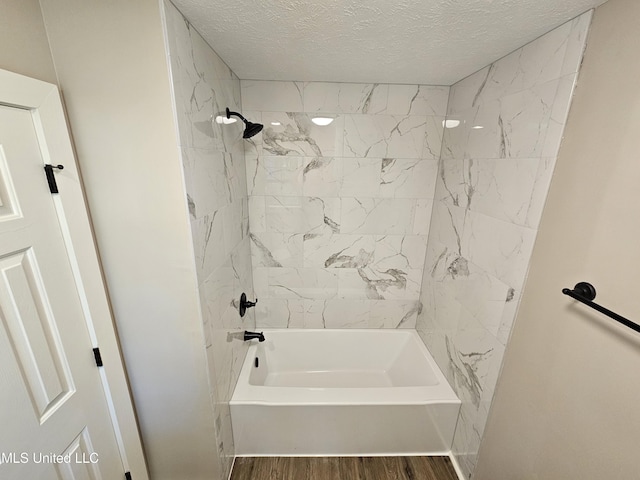 bathroom featuring hardwood / wood-style flooring, a textured ceiling, and tiled shower / bath