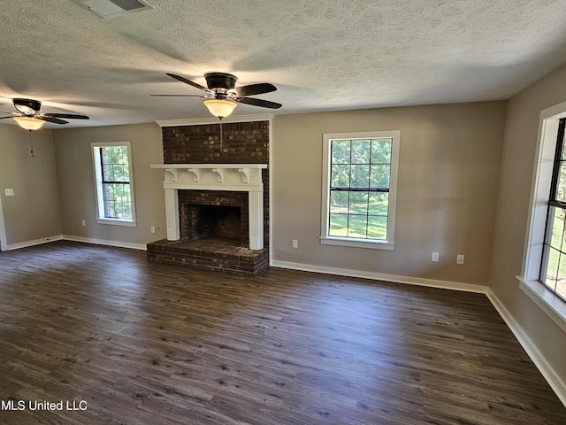 unfurnished living room featuring ceiling fan, a healthy amount of sunlight, dark hardwood / wood-style flooring, and a fireplace