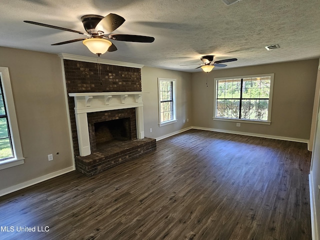 unfurnished living room with ceiling fan, a fireplace, dark wood-type flooring, and a textured ceiling